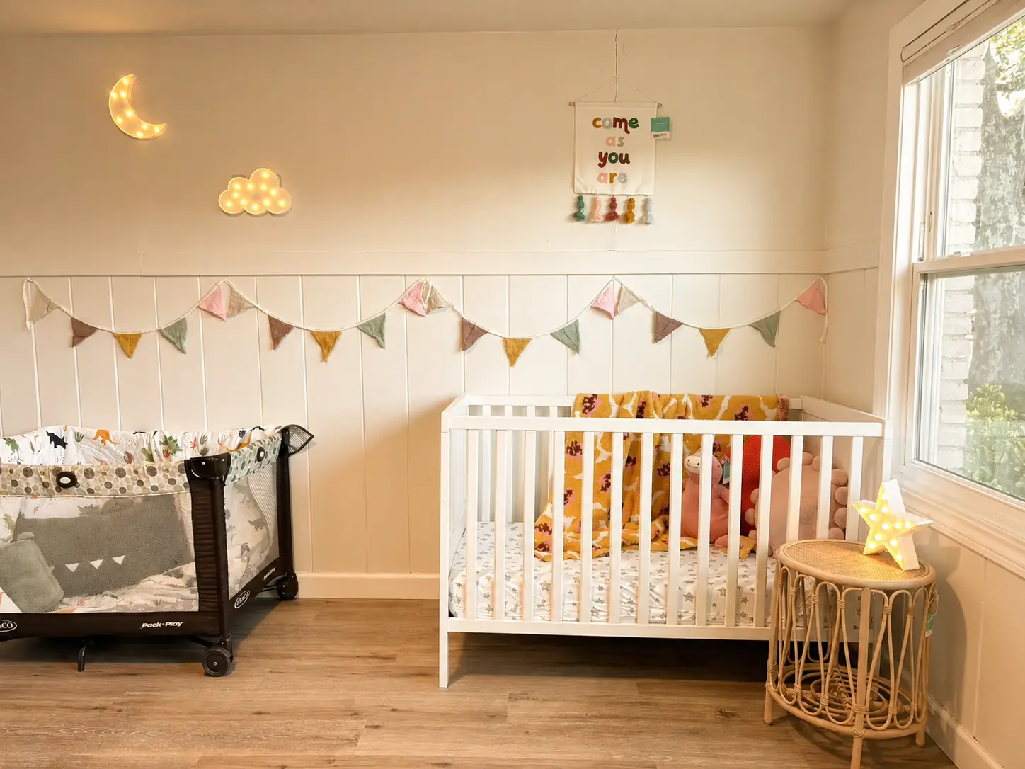 Calm infant care room with cribs, natural light, and warm decorations
