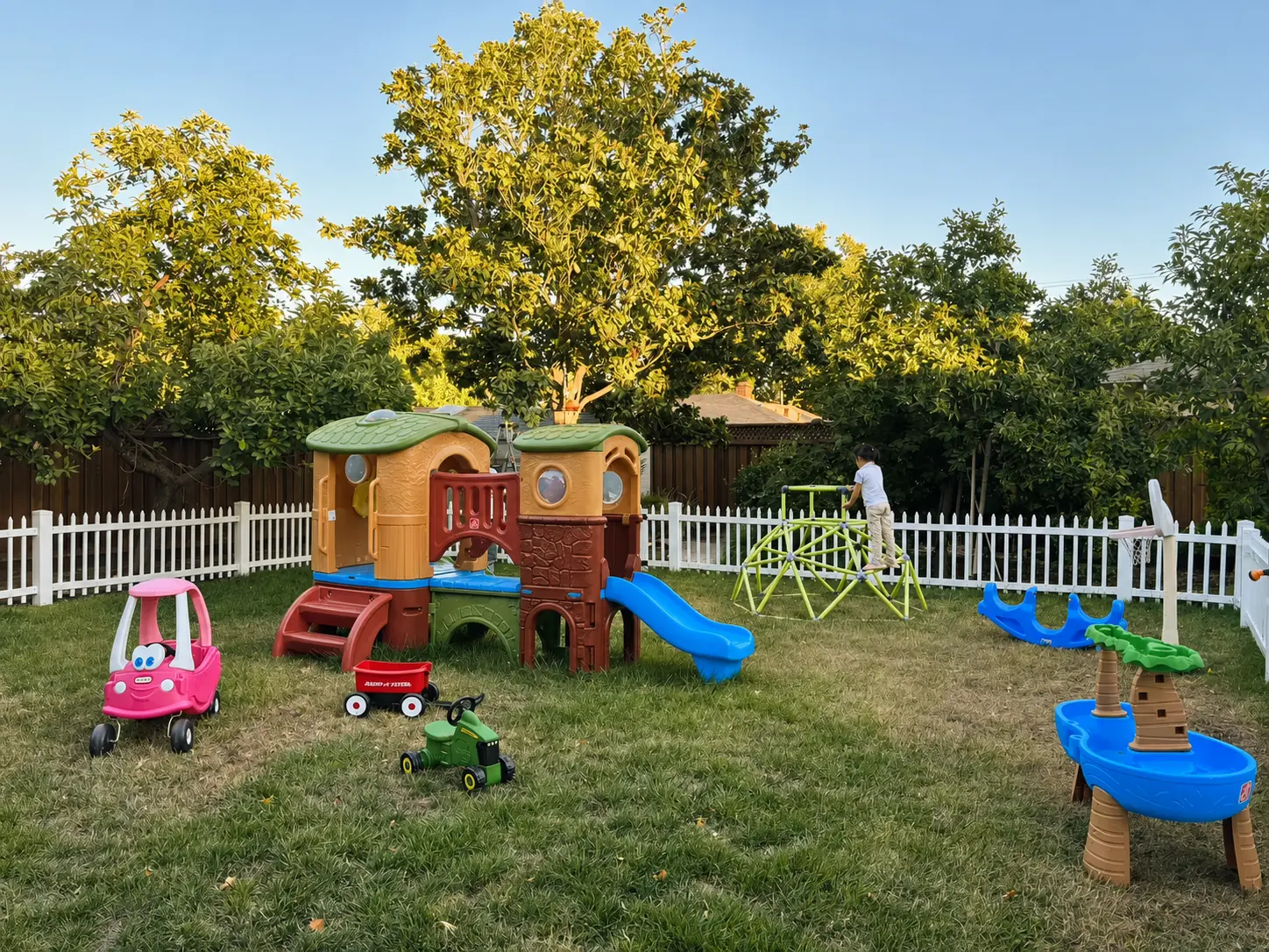 Secure fenced Dodo Kids playground with playhouse, slides, and ride-on toys